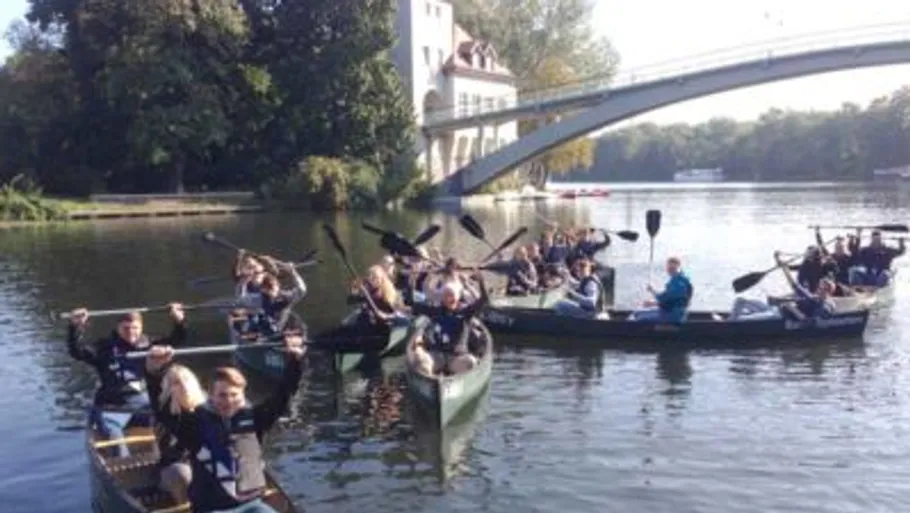Gruppe Kanufahren auf einem Fluss nahe einer Brücke.
