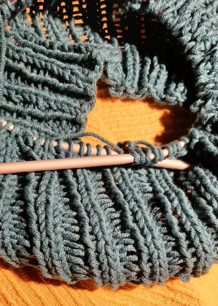 Strickprojekt mit blauem Garn auf Nadeln.