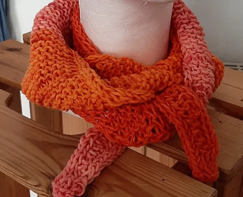 Gestrickter orangefarbener Schal auf Holzständer.