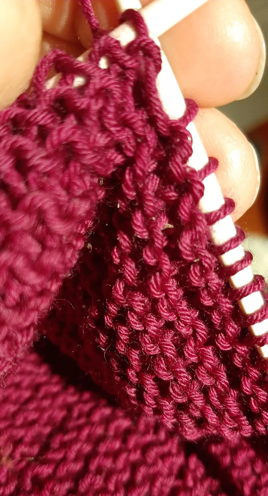 Nahaufnahme des Strickens mit rotem Garn und Nadeln.