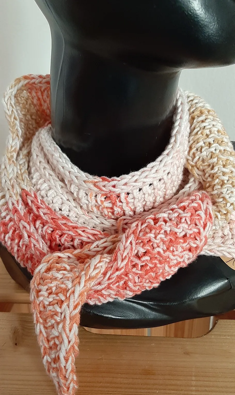 Knitted scarf on black mannequin bust.