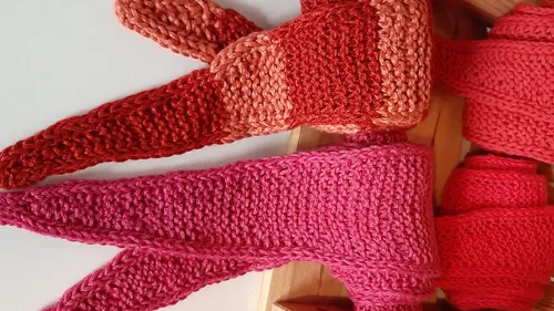 Knitted scarves rolled and draped, wooden box.