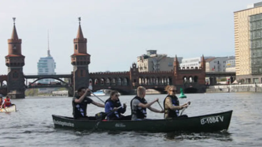 Personen paddeln Kanu nahe Stadtbrücke.