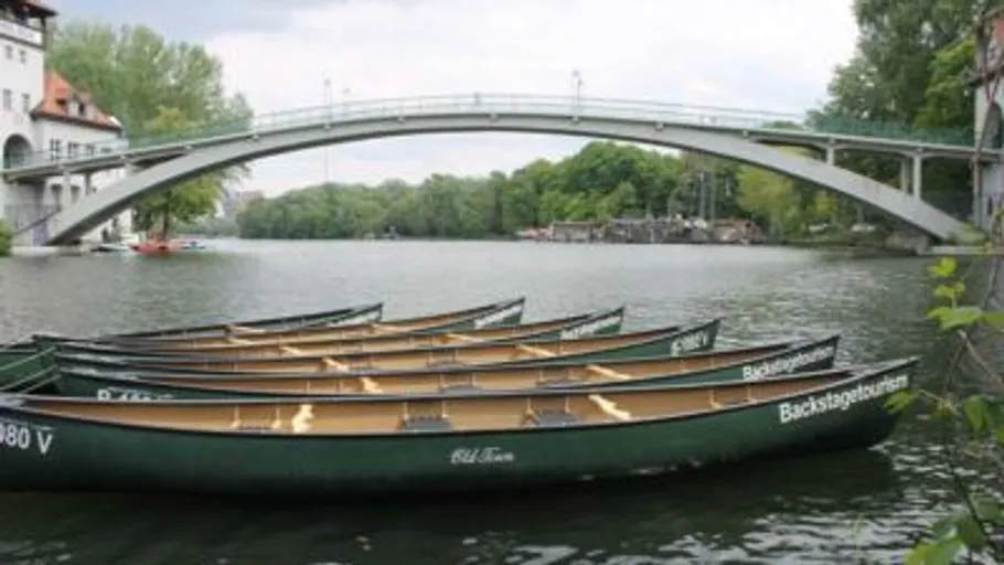 Kanus auf Fluss unter einer Bogenbrücke.