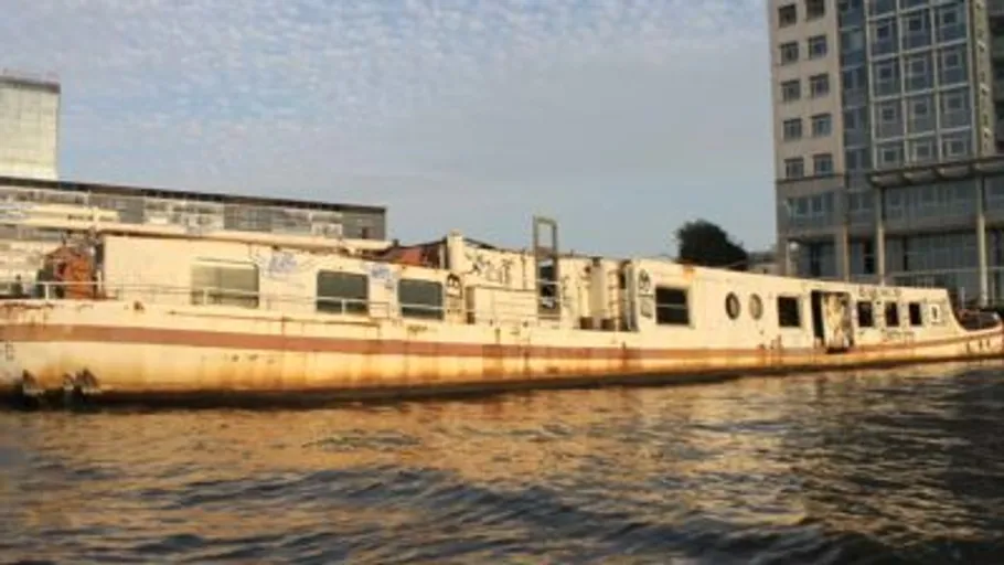 Abandoned boat floating near urban buildings.