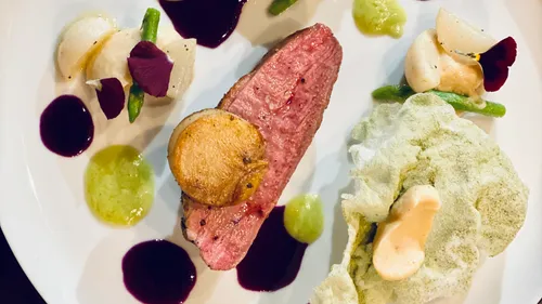 Gourmetgericht mit Fleisch, Gemüse und Sauce.