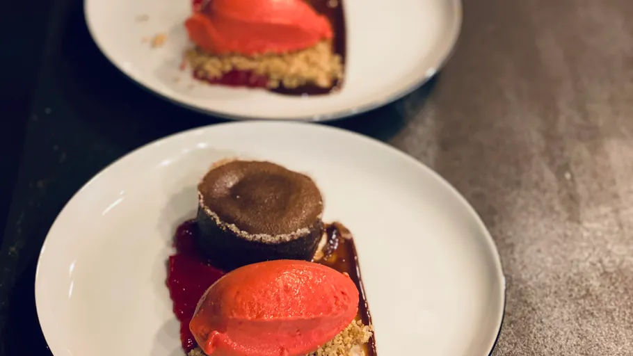 Schokoladendessert mit rotem Sorbet auf Tellern.