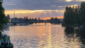 Fluss bei Sonnenuntergang mit Brücke und Bäumen.