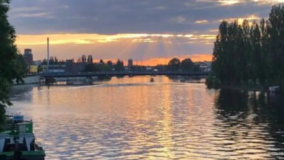 River at sunset with bridge and trees.
