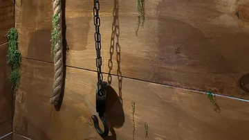 Rope and chain hanging on wooden wall.