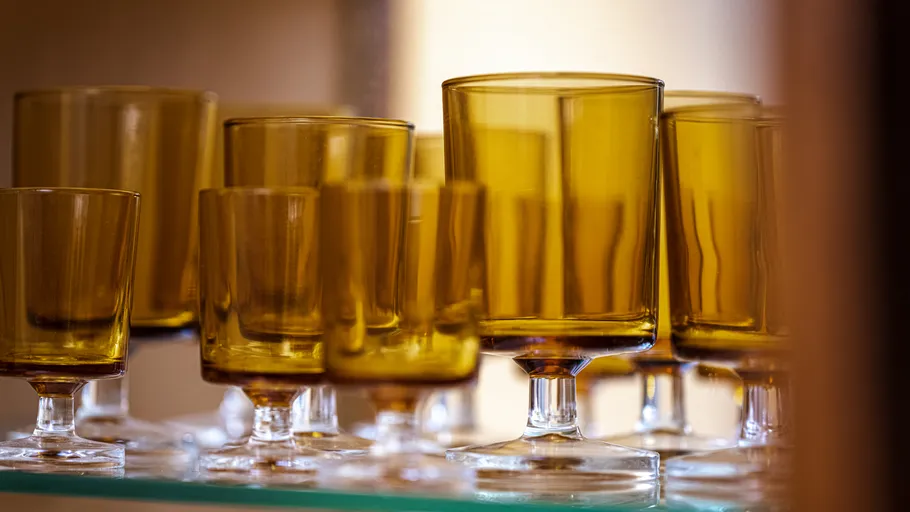 Amber glasses arranged on a glass shelf.