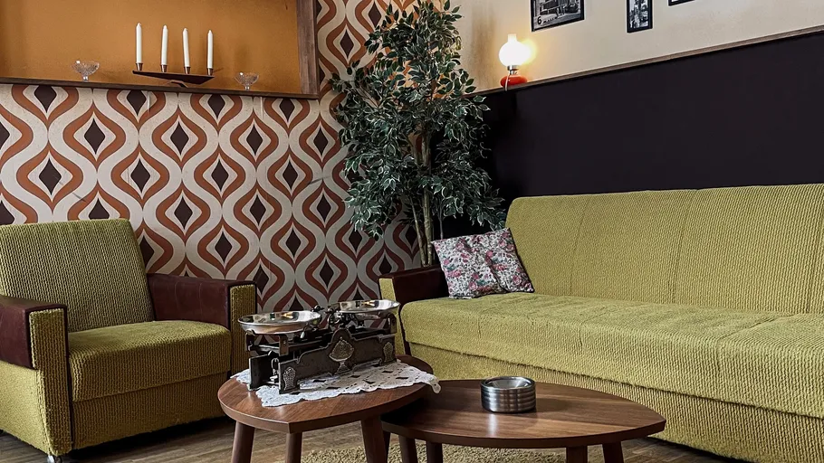 Retro-Wohnzimmer mit gemusterter Tapete, Vintage-Möbel.