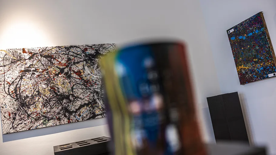 Abstract paintings on gallery walls with blurred foreground.