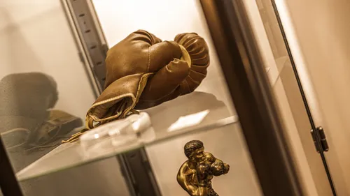 Boxing gloves displayed in glass cabinet.