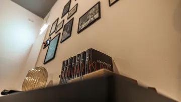 Books and photos on a tilted wall shelf.