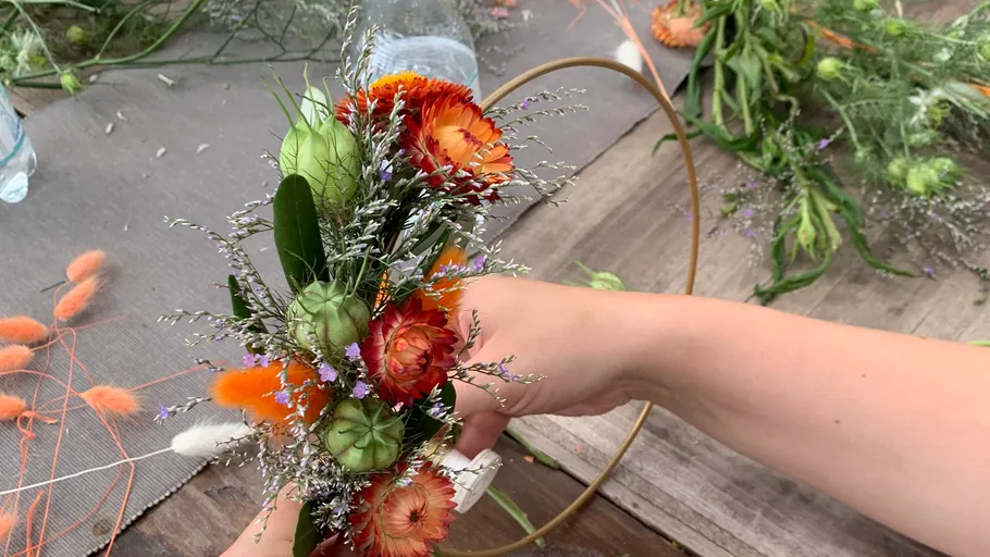 Hands arranging flowers on golden ring.