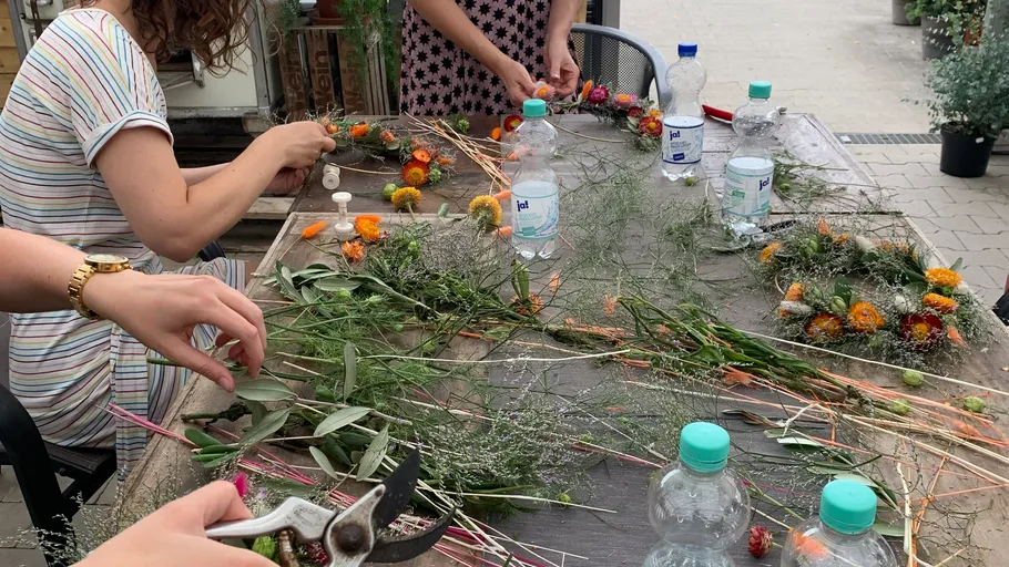 People arranging flowers on a wooden table outdoors.