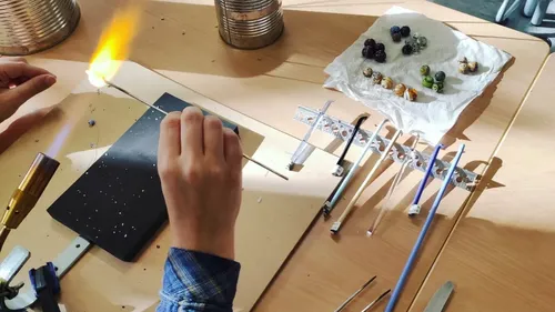 Person stellt Glasperlen mit Flammenbrenner her.