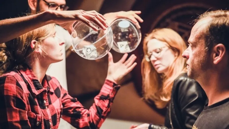 People examining dice inside transparent spheres.