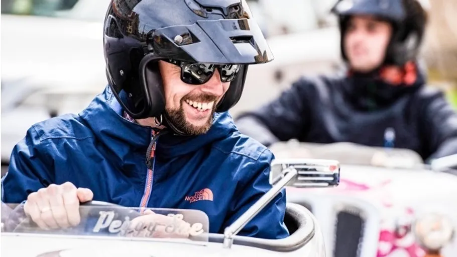 Mann fährt Gokart, lächelnd, trägt Helm.