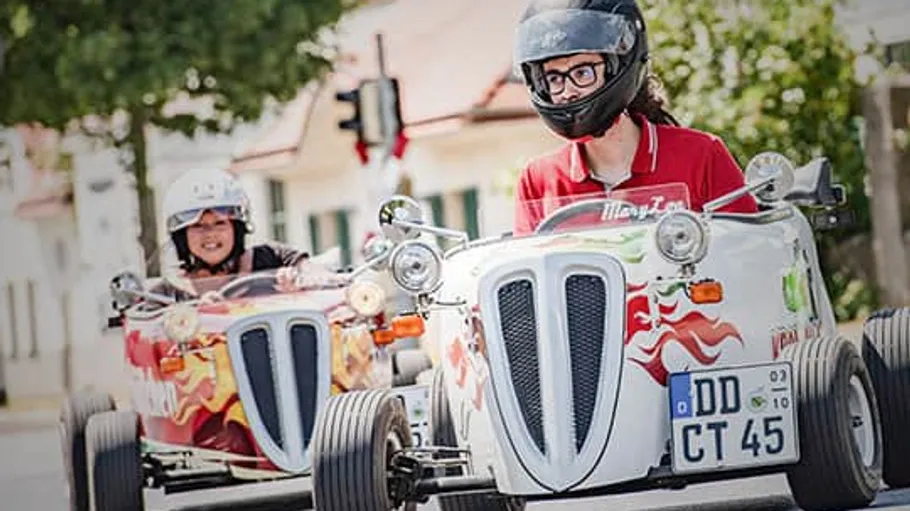 Zwei Personen fahren Miniaturautos im Freien.