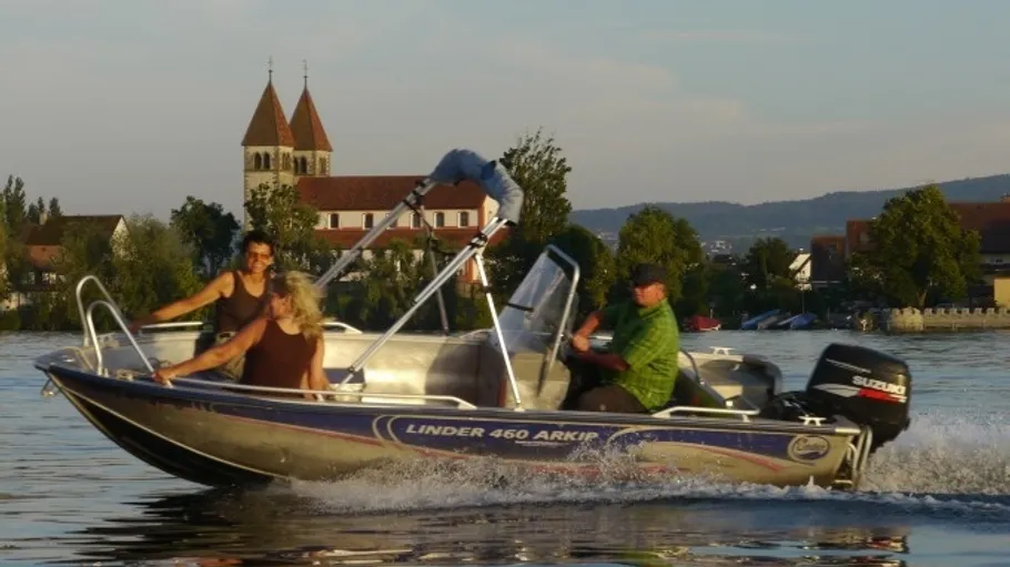 Motorboat with people on lake near church.