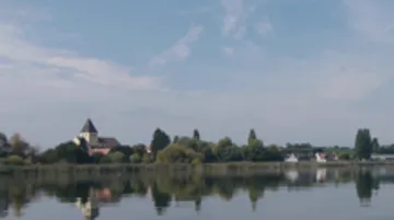 Church beside lake under a blue sky.