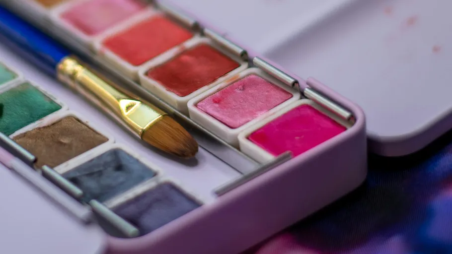 Aquarellpalette mit Pinsel auf Tisch.