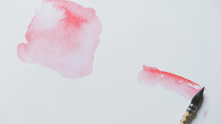 Pinsel mit roter Aquarellfarbe auf Papier.