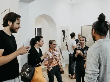 Gruppe von Menschen unterhält sich bei einer Kunstveranstaltung.