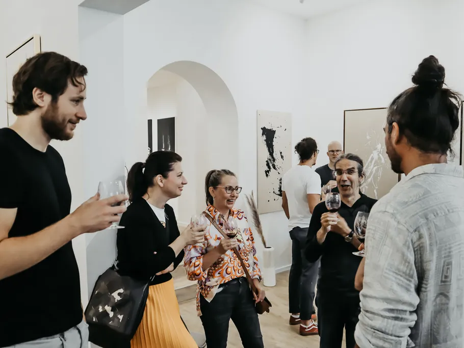 Gruppe von Menschen unterhält sich bei einer Kunstveranstaltung.