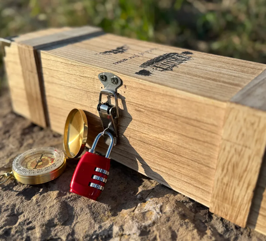 Holzkiste mit Schloss und Kompass auf Felsen.