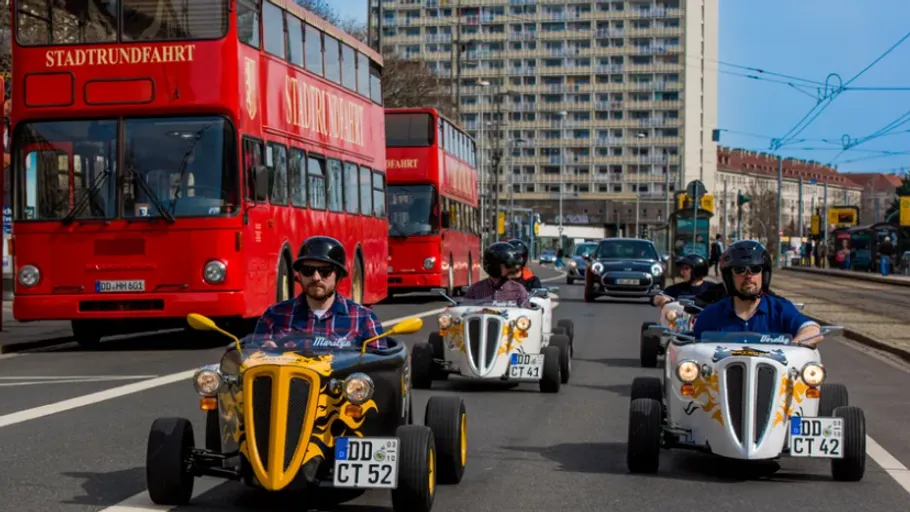 Three mini cars driving on city street.