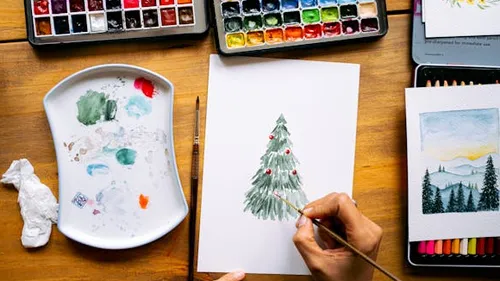 Person malt Weihnachtsbaum mit Aquarellfarben.