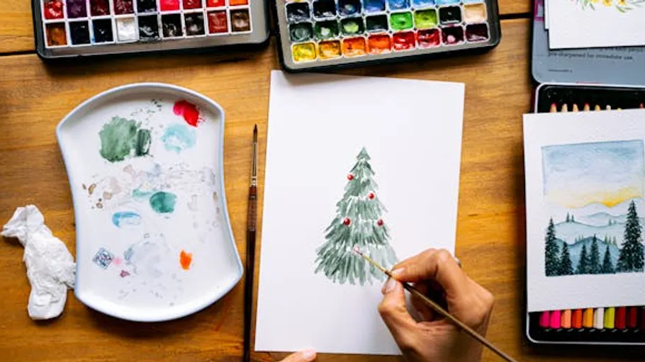 Person malt Weihnachtsbaum mit Aquarellfarben.