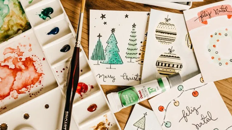 Paint palette with Christmas cards on table.