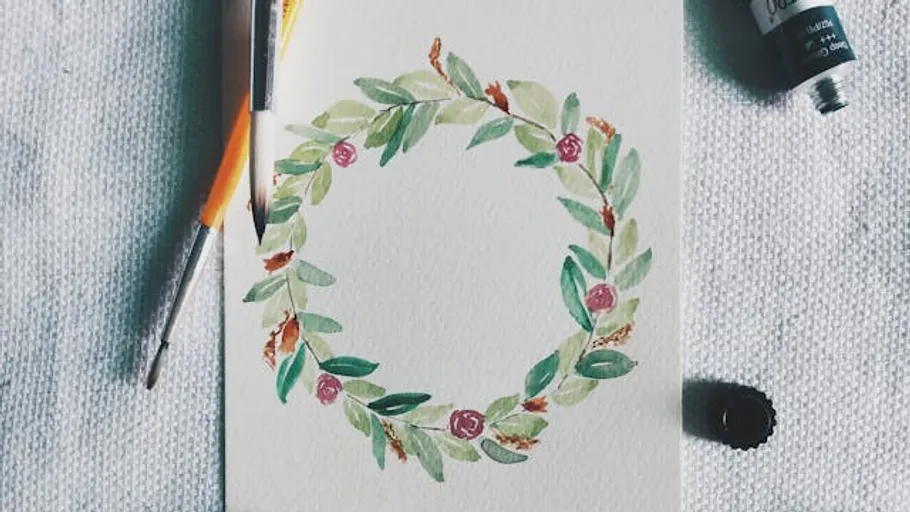 Aquarell-Blumenkranz auf Papier mit Pinseln.