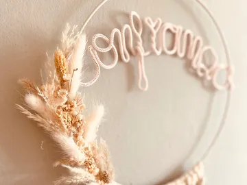 Wall decoration with dried flowers and lettering in pastel shades.