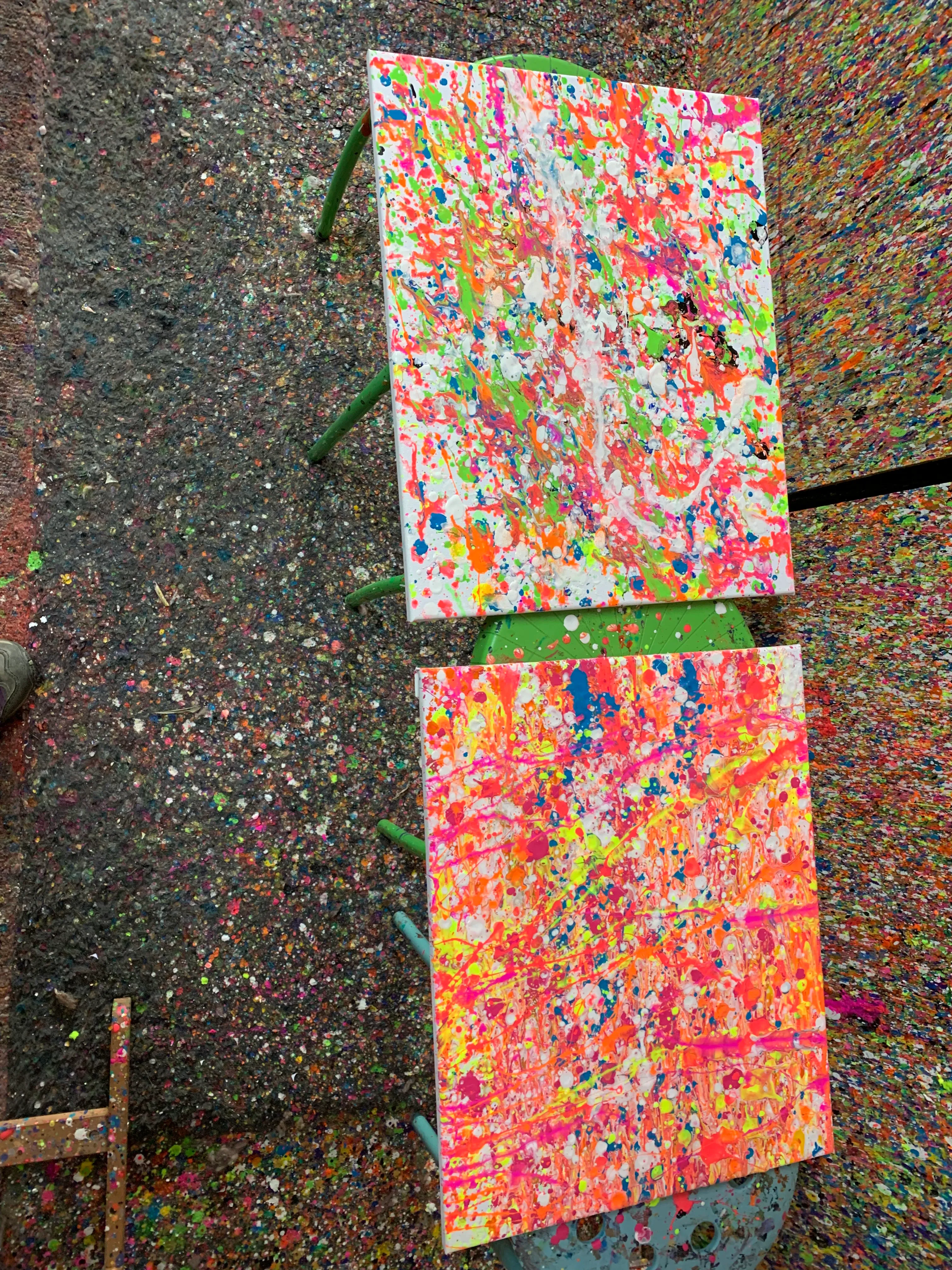 Two colorful canvases on splattered floor.