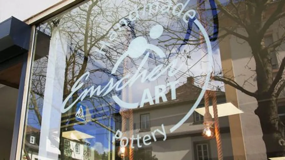 Shop window with pottery store sign reflection.