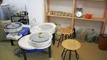 Pottery studio with wheels and shelves.