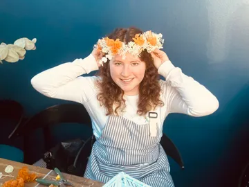 Woman wearing a wreath of flowers and smiling at the table.