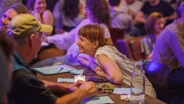 People smiling at table in crowded room.