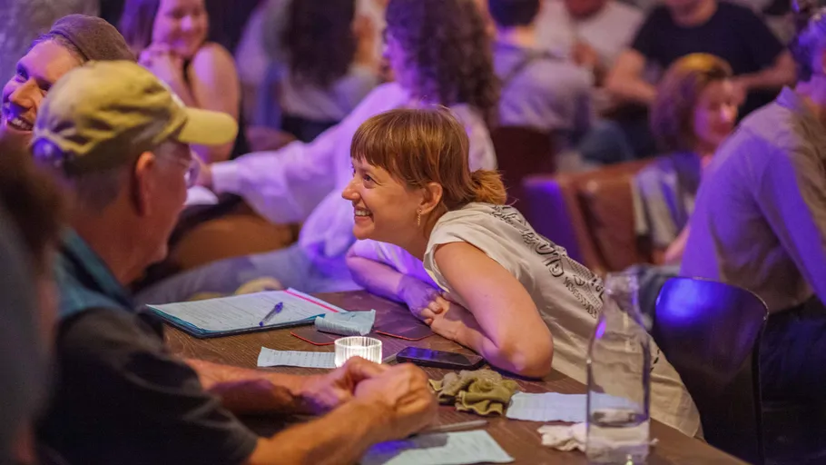 People smiling at table in crowded room.