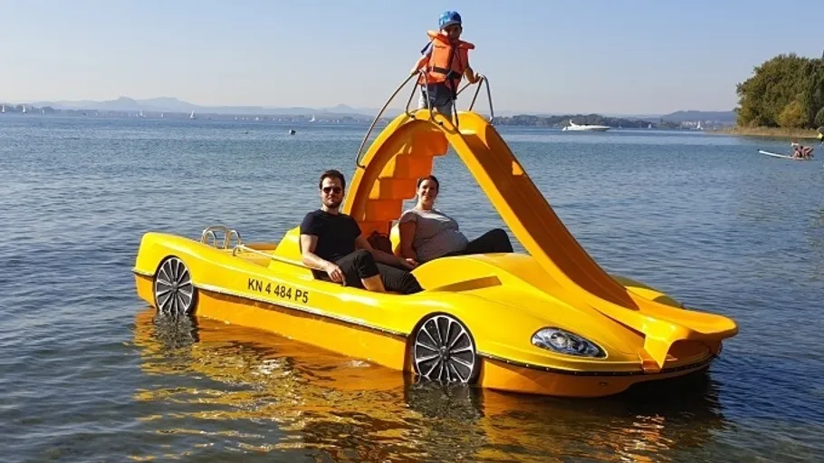 Two adults and child on yellow pedal boat.