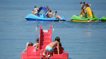Personen auf Tretbooten mit Rutschen im Wasser.