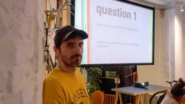 Man in cap near projected quiz question inside room.