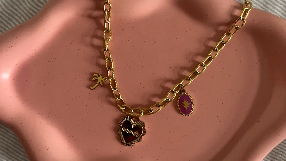 Gold chain necklace on a pink tray.