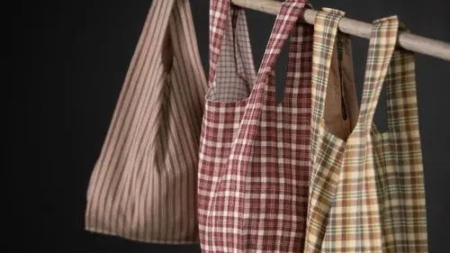Karierte Taschen hängen an einem Holzstab.