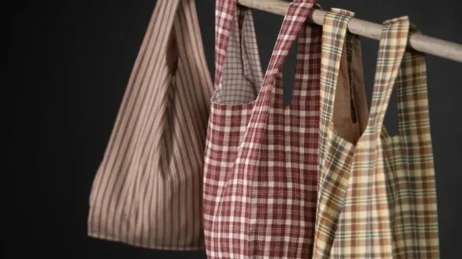 Karierte Taschen hängen an einem Holzstab.